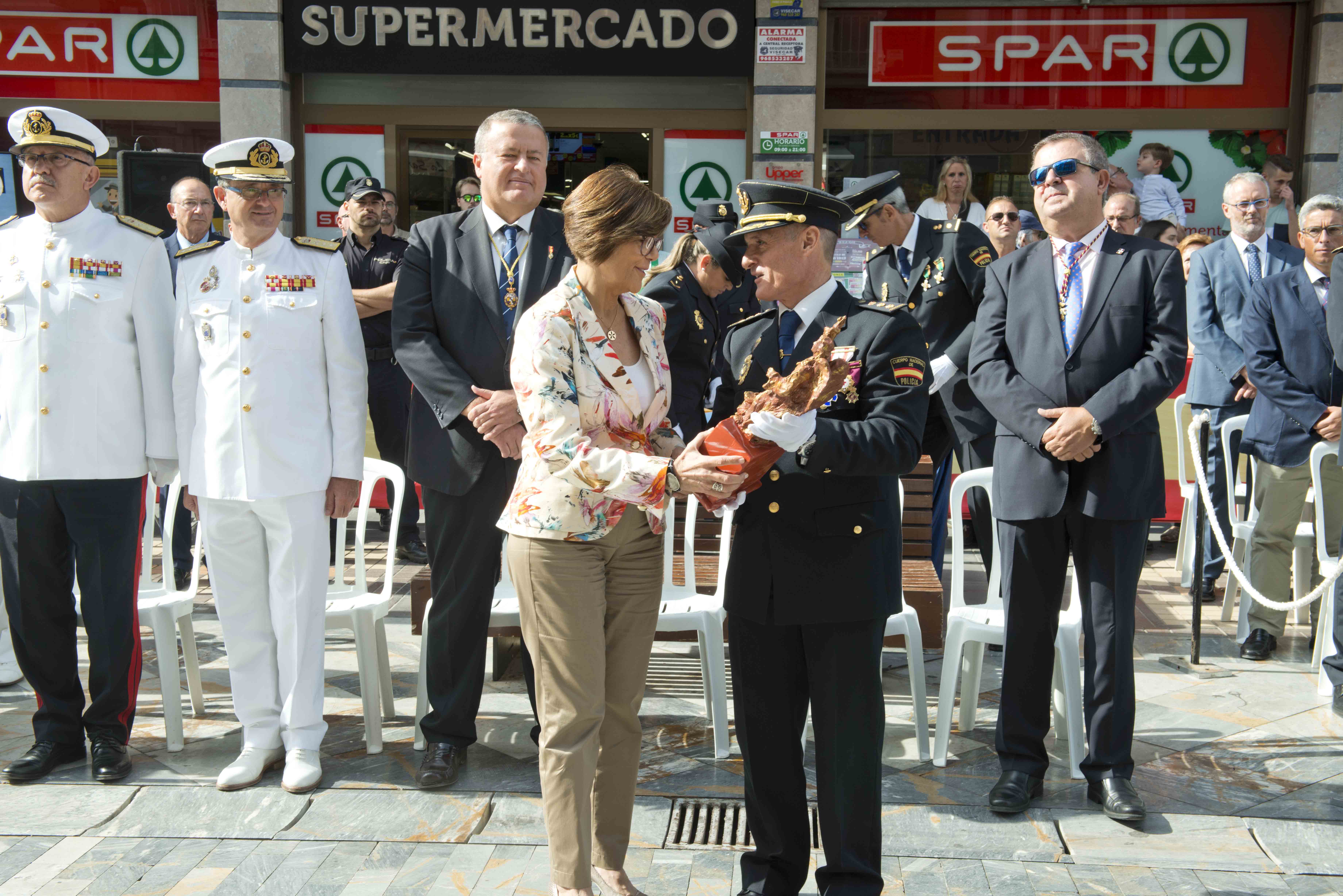 La presidenta de la Cámara, Rosa Peñalver, recoge la imagen del Santo Ángel Custodio de manos del comisario, jefe de la Comisaría de Cartagena, Ignacio del Olmo