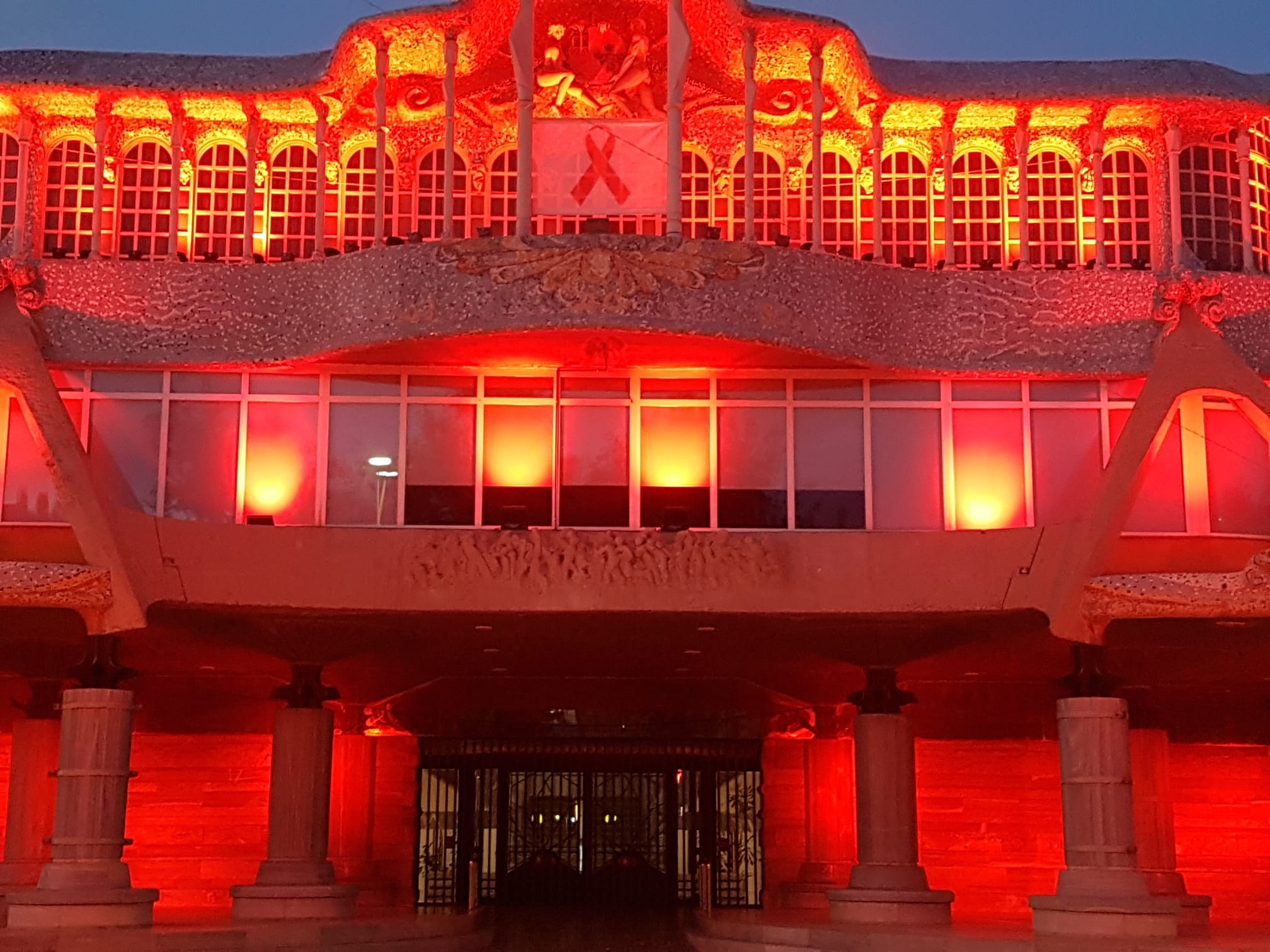 La fachada principal de la Asamblea Regional se ha iluminado de rojo, en solidaridad con los afectados por la enfermedad del Sida