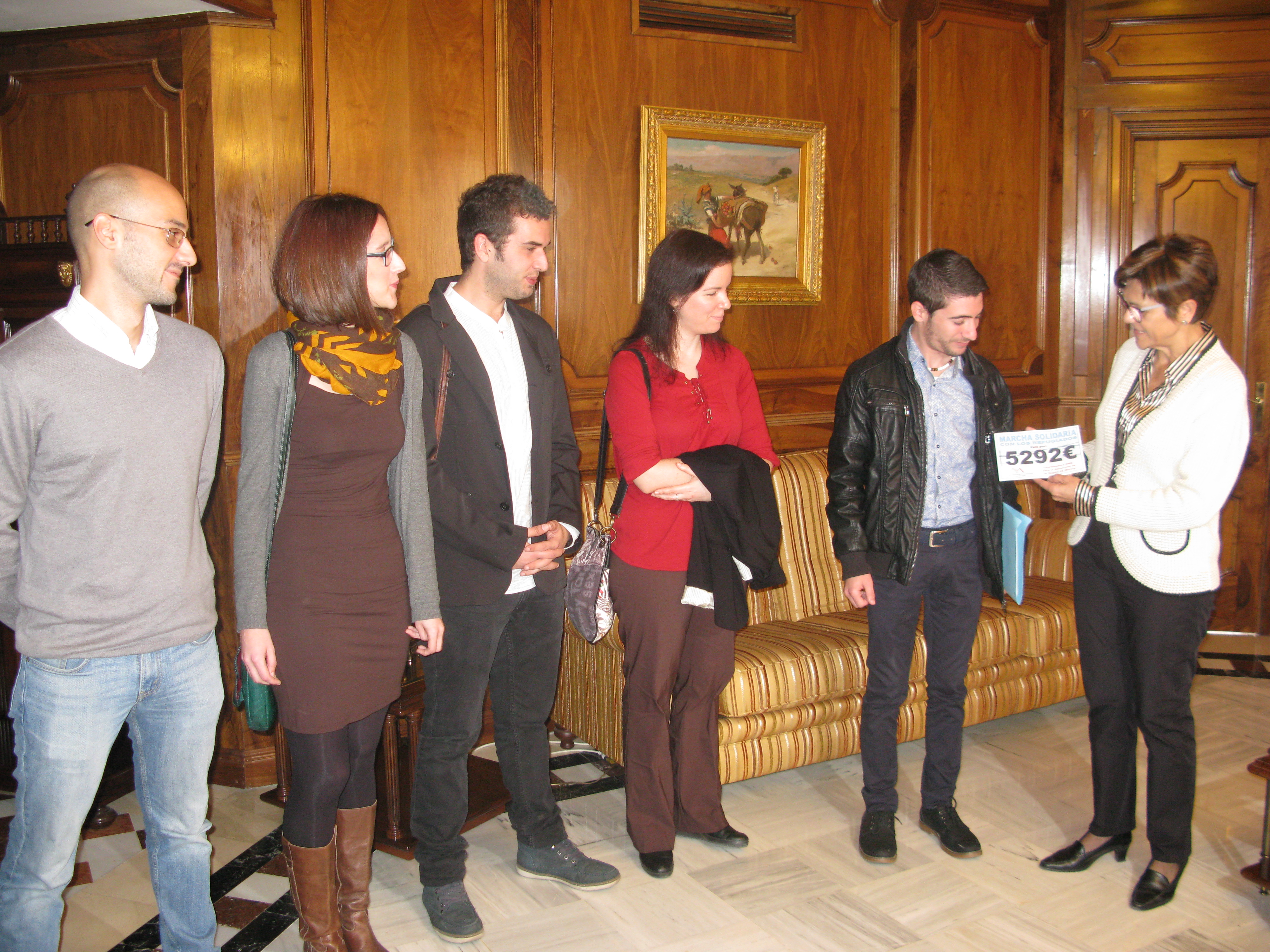 La presidenta de la Asamblea, Rosa Peñalver haciendo entrega de un dorsal con la cantidad recaudada en la Marcha por los refugiados.