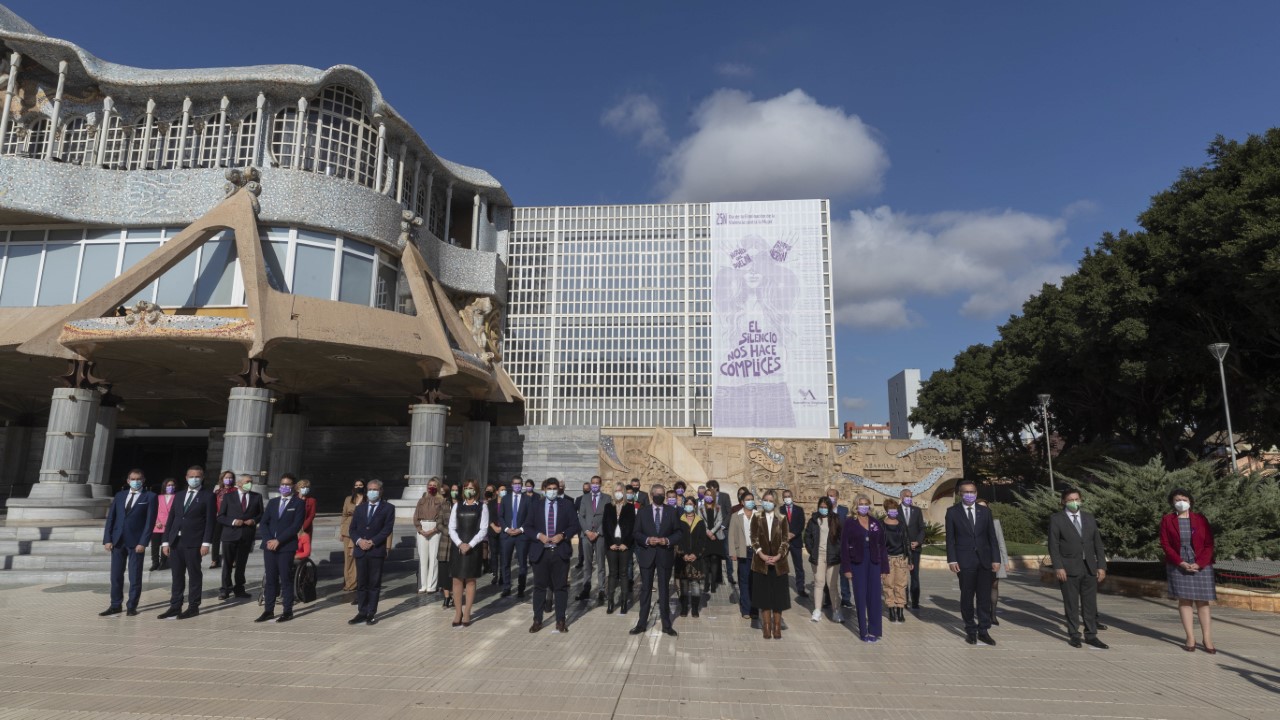 Foto de familia ante el caligrama sobre la violencia de género, colgado en la fachada de la Asamblea