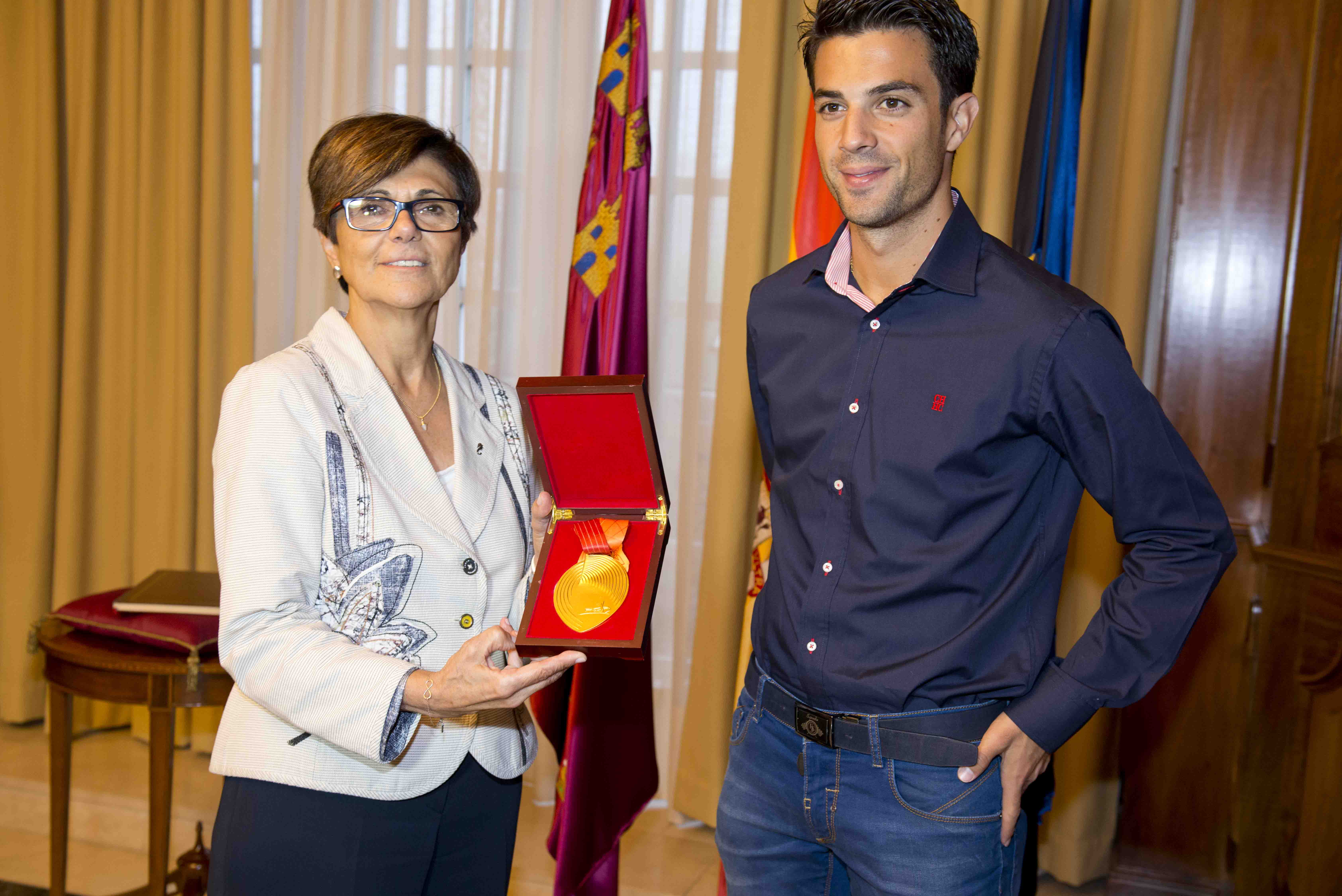 La presidenta de la Asamblea Regional muestra la medalla de oro ganada por Miguel Angel López en Pekín.