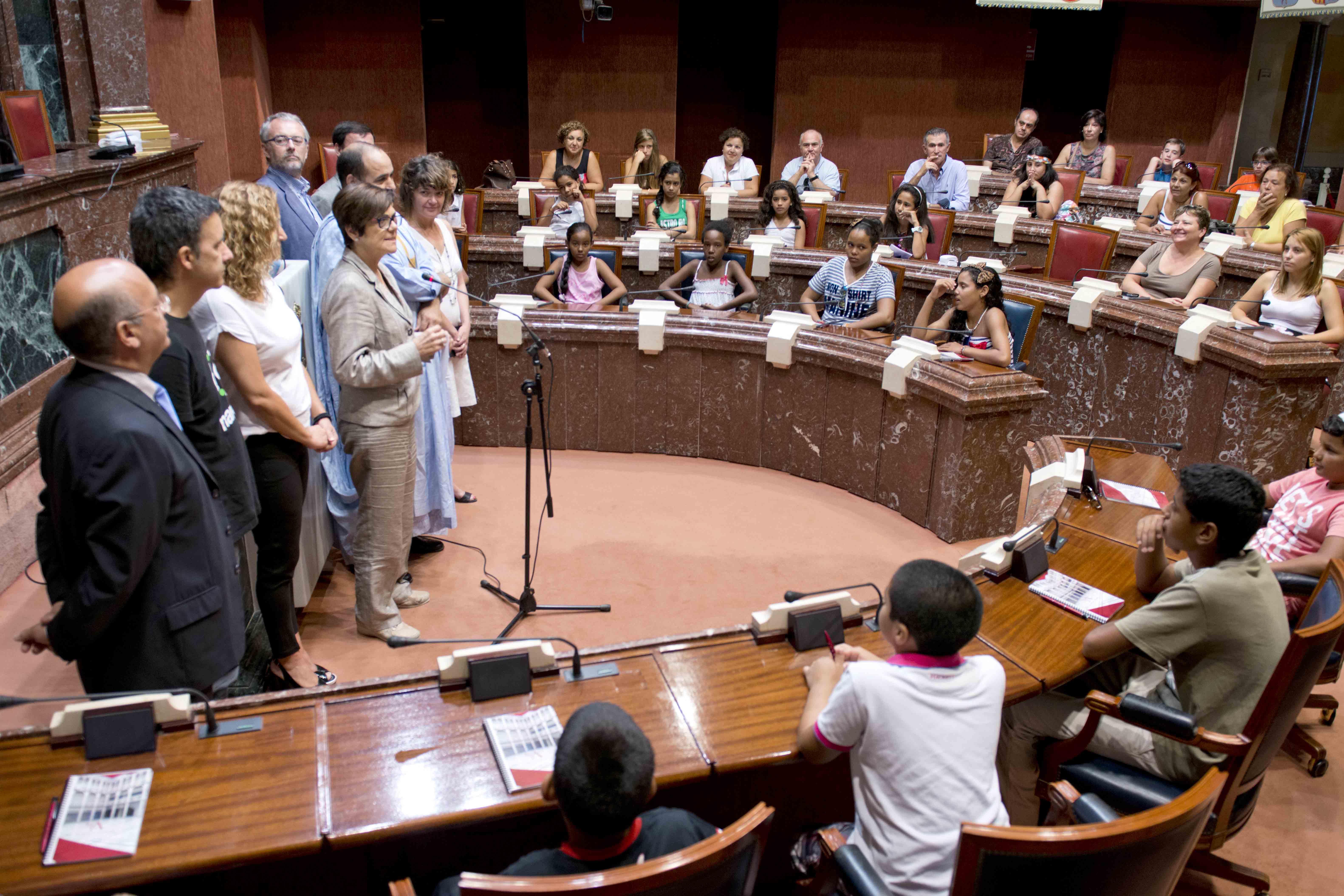 La presidenta de la Asamblea se dirige a los niños saharauis y a sus familias de acogida, junto a diputados de distintos grupos parlamentarios